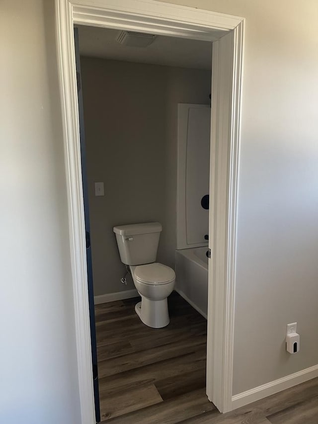 bathroom featuring hardwood / wood-style flooring, toilet, and a tub