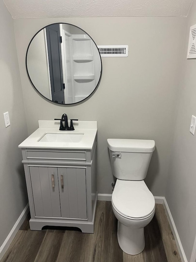 bathroom with wood-type flooring, vanity, a textured ceiling, and toilet