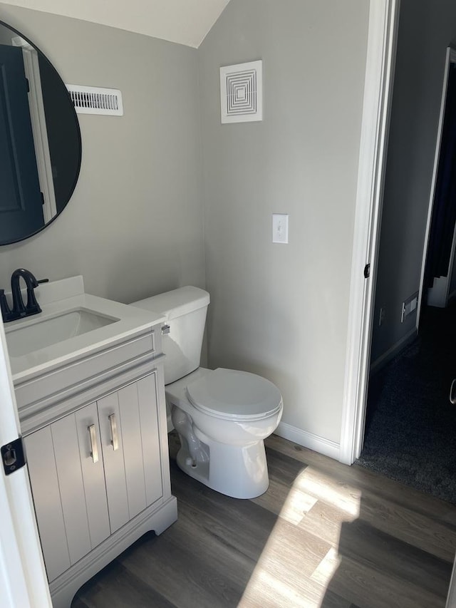 bathroom featuring toilet, vanity, lofted ceiling, and hardwood / wood-style flooring