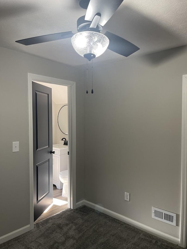 unfurnished bedroom with connected bathroom, ceiling fan, sink, a textured ceiling, and dark carpet