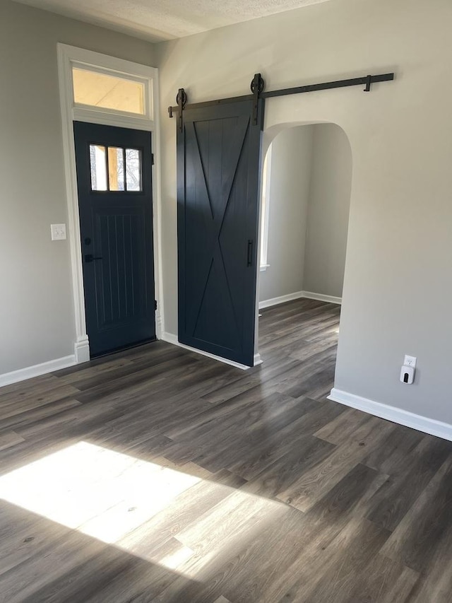 foyer with a barn door, dark wood-type flooring, and a textured ceiling