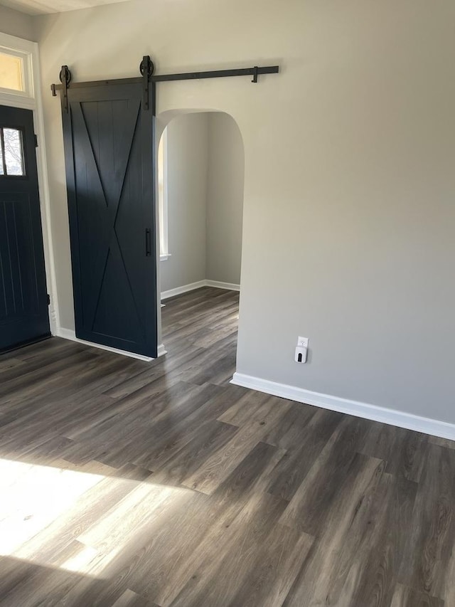 foyer entrance featuring a barn door and dark wood-type flooring