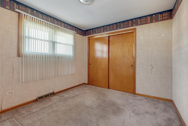 unfurnished bedroom with light carpet and a closet