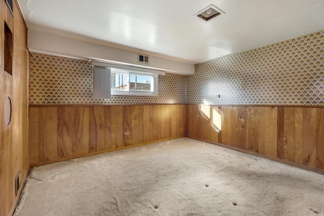 carpeted spare room featuring wooden walls