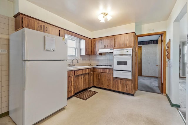 kitchen with decorative backsplash, white appliances, and sink