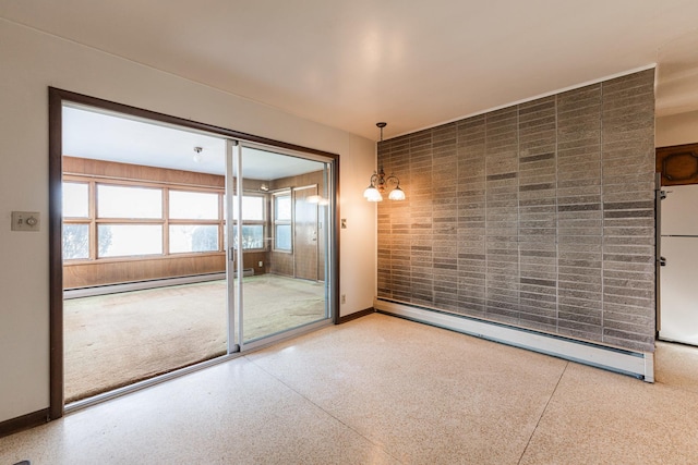 empty room featuring a chandelier and baseboard heating