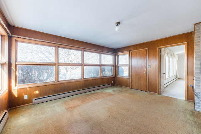 unfurnished room featuring a baseboard heating unit, wooden walls, and light carpet