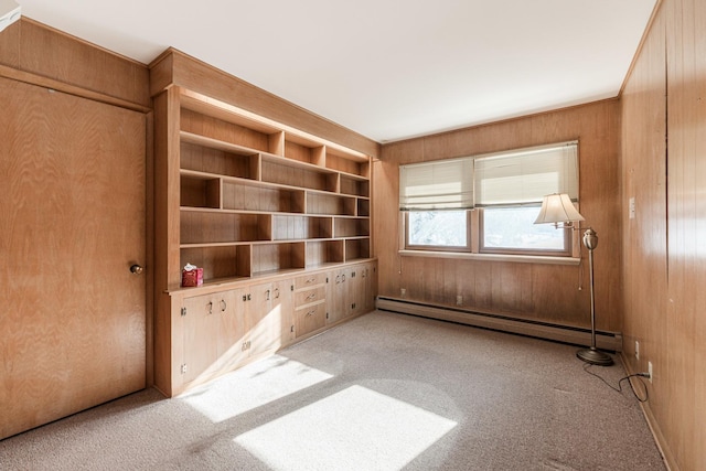 spare room with baseboard heating, light colored carpet, built in features, and wooden walls