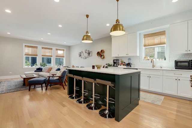 kitchen with a kitchen island, plenty of natural light, pendant lighting, and white cabinetry