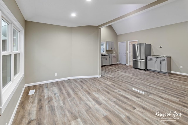 unfurnished living room featuring light wood-type flooring and vaulted ceiling