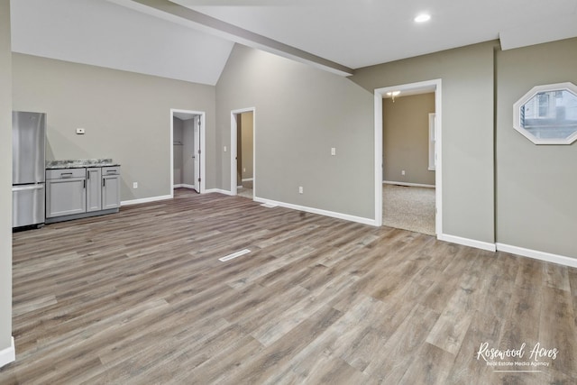 unfurnished living room featuring lofted ceiling and light wood-type flooring