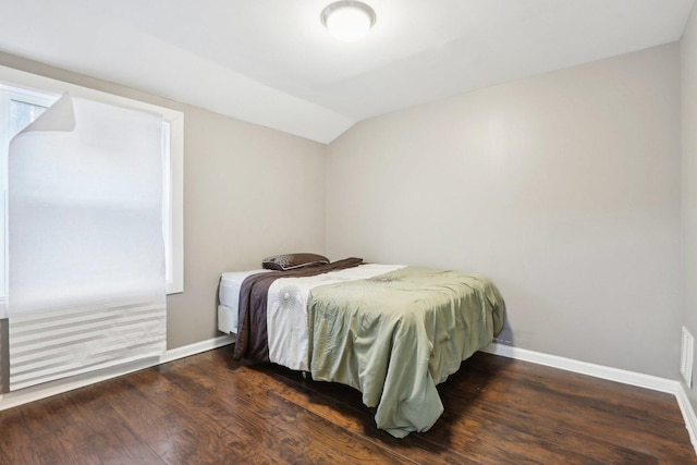 bedroom with dark wood-type flooring and lofted ceiling