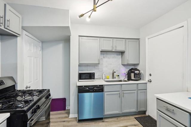 kitchen featuring backsplash, stainless steel appliances, light hardwood / wood-style floors, and sink