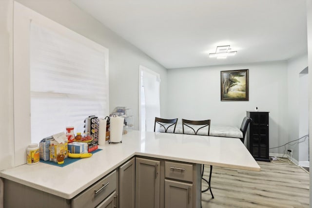 kitchen featuring a kitchen bar, kitchen peninsula, and light hardwood / wood-style flooring