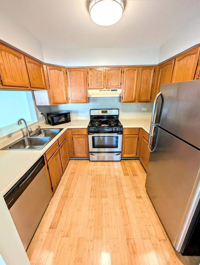 kitchen with appliances with stainless steel finishes, light hardwood / wood-style floors, and sink