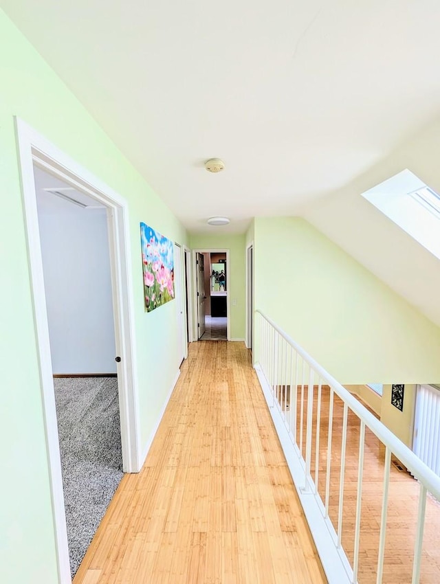 hallway featuring light hardwood / wood-style floors and vaulted ceiling