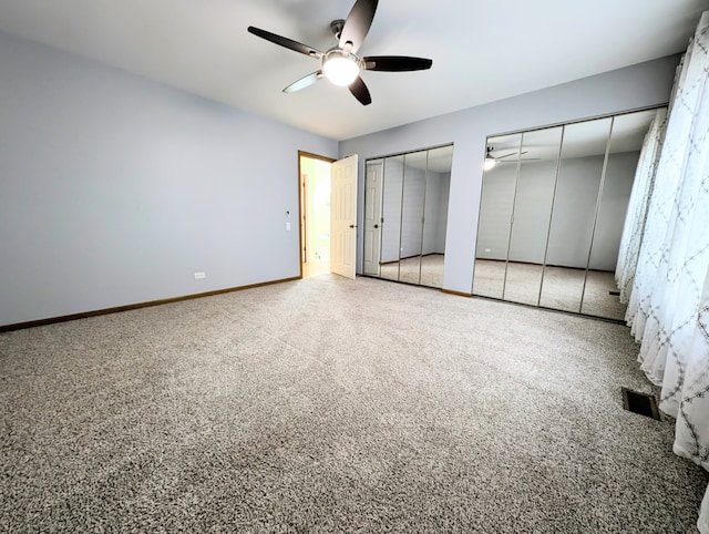 unfurnished bedroom with carpet flooring, two closets, and ceiling fan