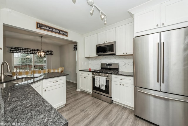 kitchen featuring tasteful backsplash, dark stone counters, stainless steel appliances, sink, and white cabinetry