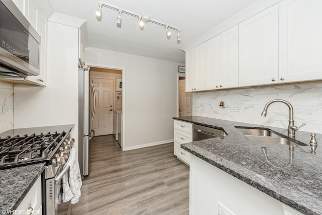 kitchen featuring sink, stainless steel appliances, tasteful backsplash, dark stone counters, and white cabinets