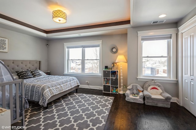 bedroom with dark hardwood / wood-style floors and a tray ceiling