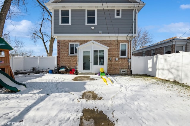 snow covered house with a playground