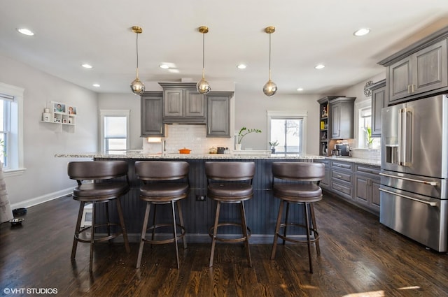 kitchen with decorative light fixtures, a kitchen bar, tasteful backsplash, and high end fridge