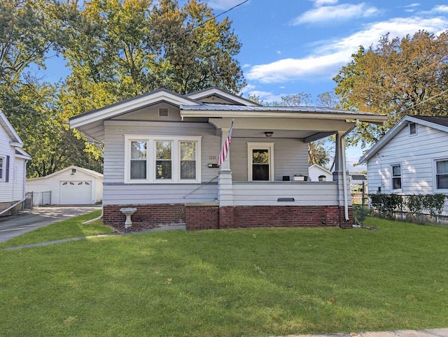 bungalow featuring covered porch, a garage, a front lawn, and an outdoor structure