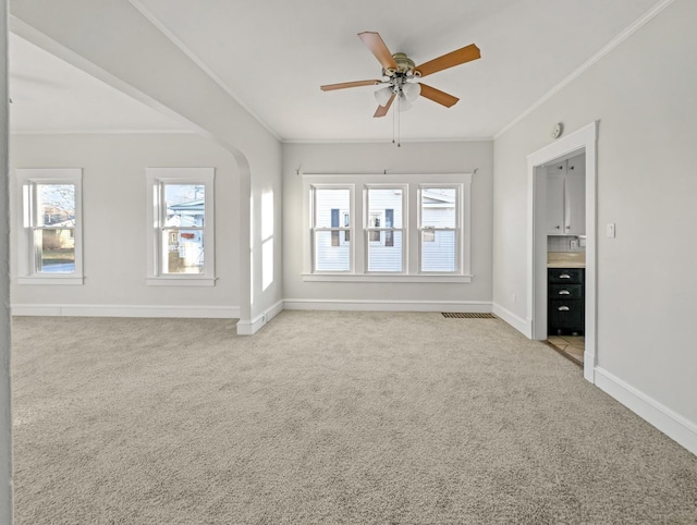 unfurnished living room featuring ceiling fan, a healthy amount of sunlight, crown molding, and light carpet