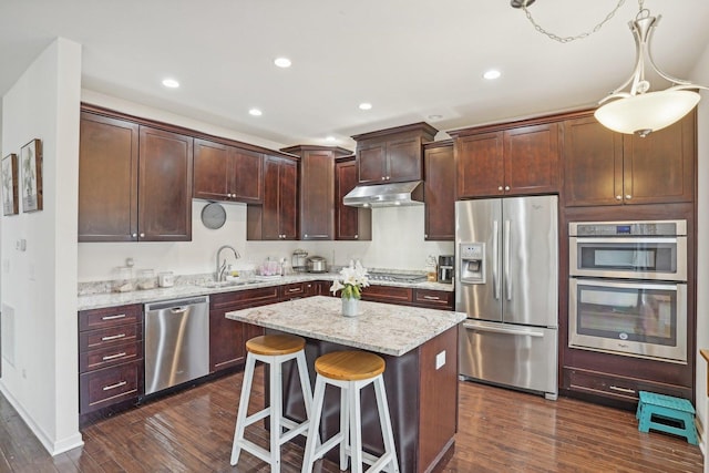 kitchen featuring appliances with stainless steel finishes, dark wood-type flooring, sink, a kitchen island, and hanging light fixtures