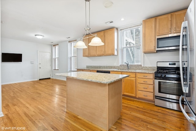 kitchen with stainless steel appliances, sink, a center island, light hardwood / wood-style floors, and hanging light fixtures