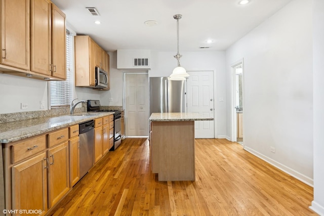 kitchen featuring pendant lighting, a center island, stainless steel appliances, and light wood-type flooring