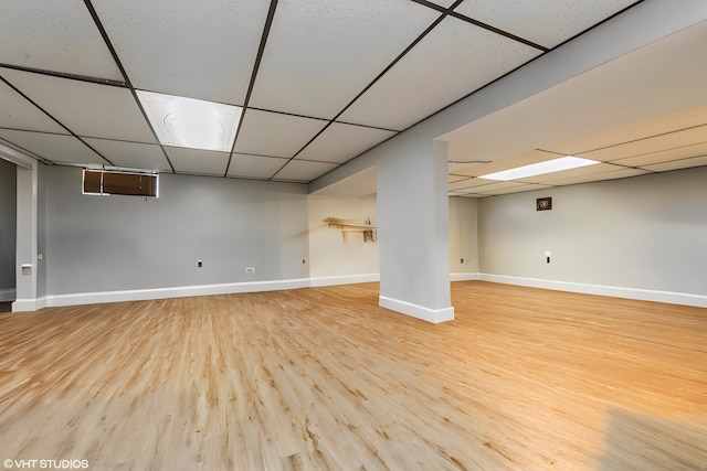 basement with a paneled ceiling and light wood-type flooring