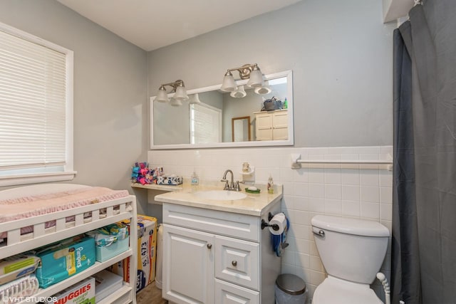 bathroom with vanity, toilet, and tile walls