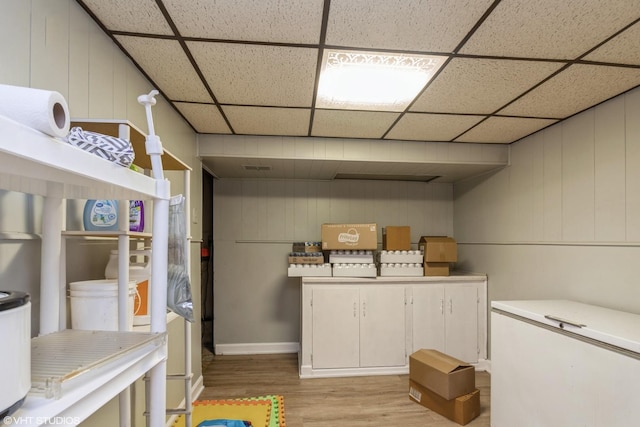 laundry area featuring light wood-type flooring and wooden walls