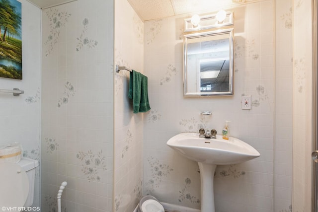 bathroom with toilet and tile walls