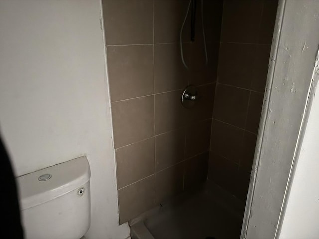 bathroom with tiled shower and toilet