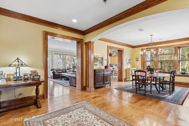 dining area with an inviting chandelier, ornamental molding, and light hardwood / wood-style floors