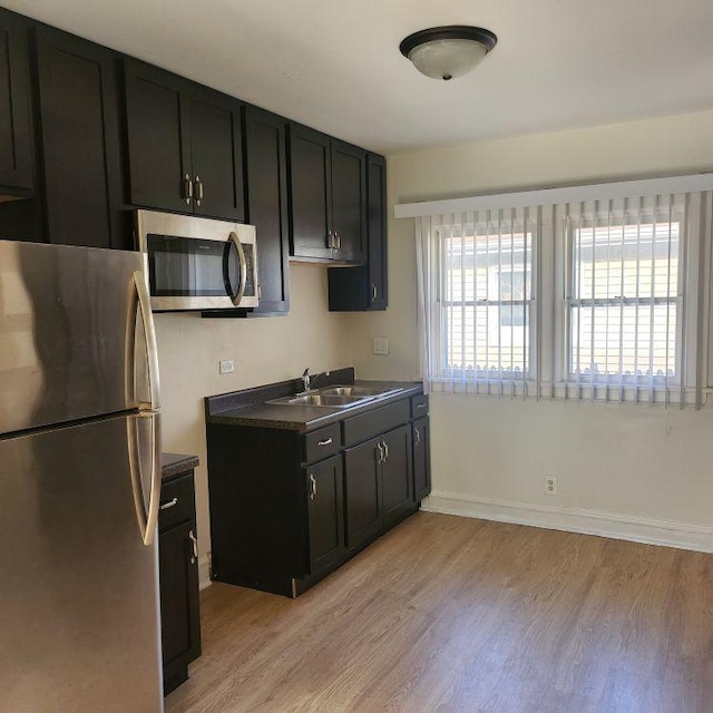 kitchen with appliances with stainless steel finishes, light hardwood / wood-style floors, and sink