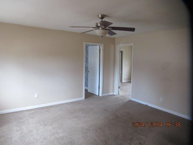 carpeted spare room with ceiling fan