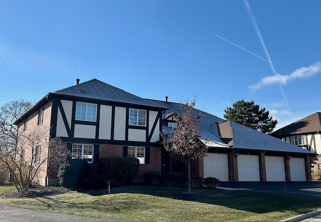 tudor home with a front yard and a garage