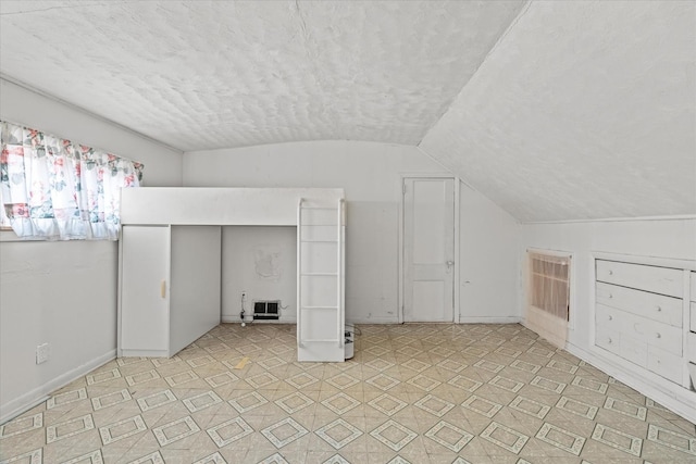 additional living space with a textured ceiling and lofted ceiling