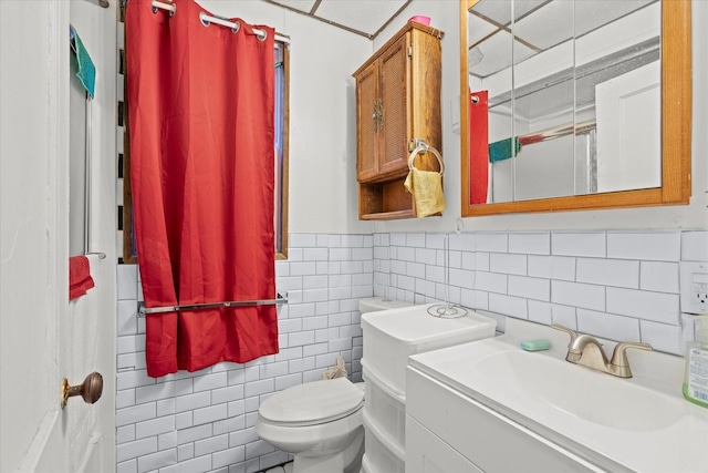 bathroom with vanity, tile walls, and toilet