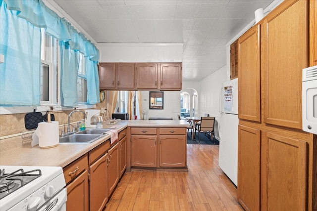 kitchen with white refrigerator, sink, light hardwood / wood-style flooring, decorative backsplash, and kitchen peninsula