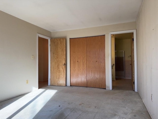 unfurnished bedroom featuring a closet, light colored carpet, and connected bathroom