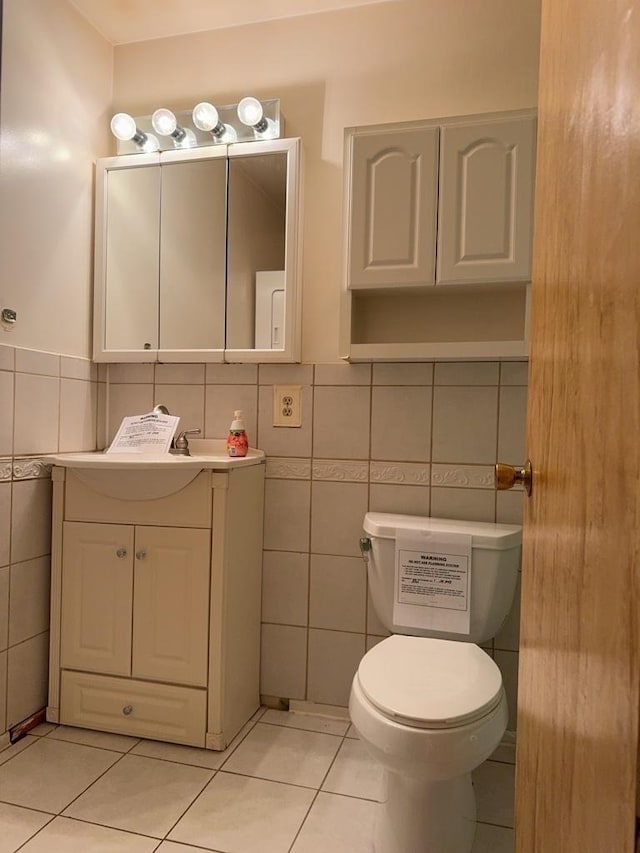 bathroom with vanity, tile patterned floors, toilet, and tile walls