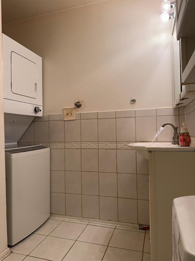 bathroom featuring tile patterned floors, a wainscoted wall, tile walls, and stacked washer and clothes dryer