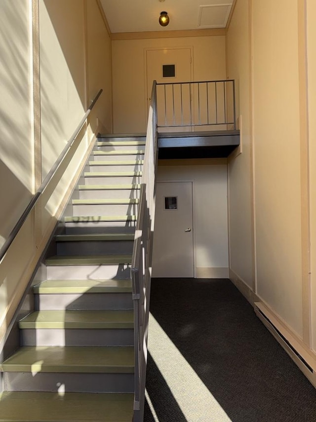 staircase with baseboard heating and carpet floors