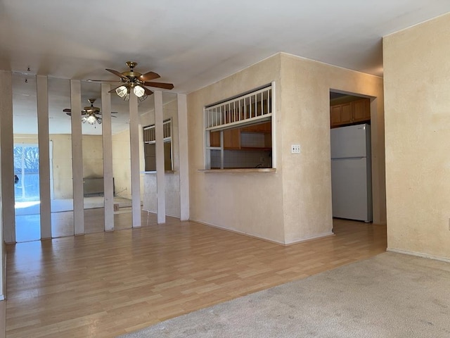 empty room with a textured wall, ceiling fan, and light wood finished floors