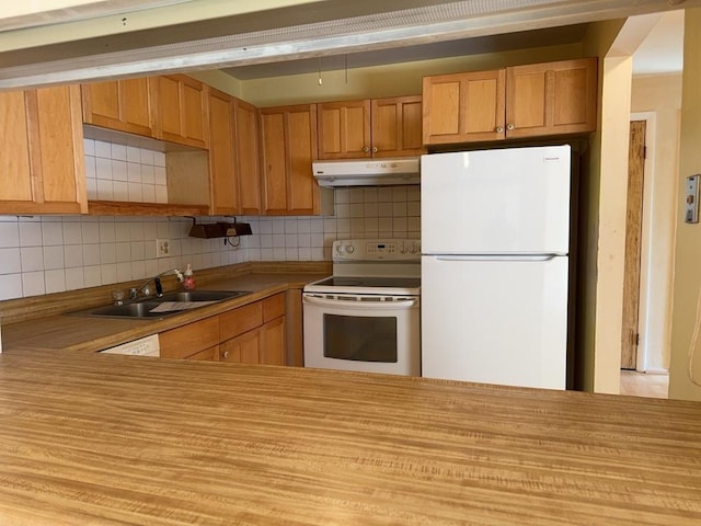 kitchen with under cabinet range hood, light countertops, decorative backsplash, white appliances, and a sink