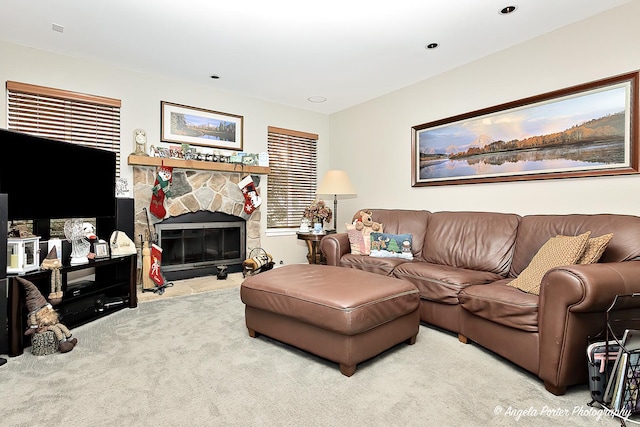 carpeted living room with a stone fireplace